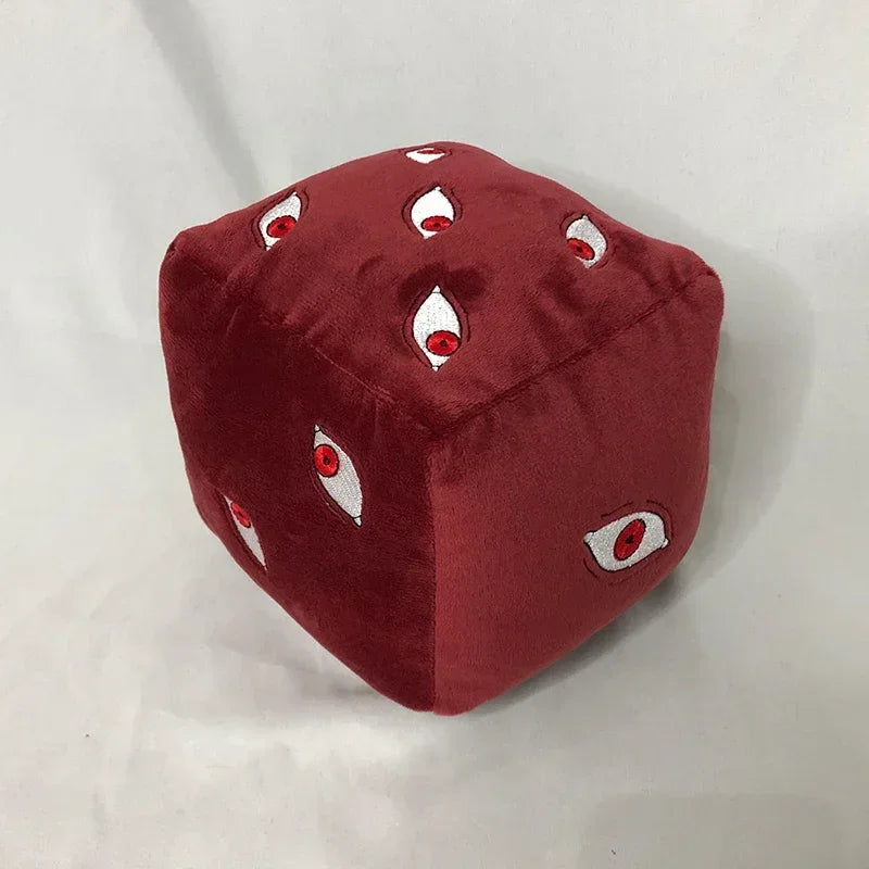 Coussin cube rouge en tissu doux, motifs d’yeux rouges et blancs sur la housse.