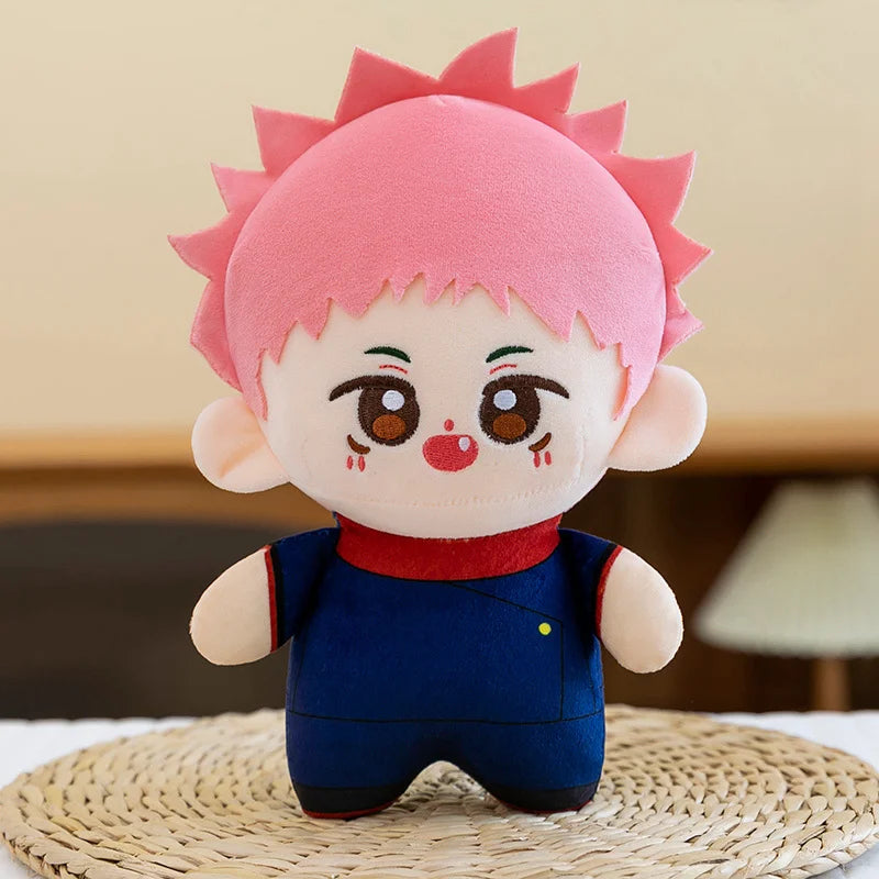 Peluche Yuji Itadori Kawai à cheveux roses, grand yeux bruns, tenue bleu marine et col rouge.