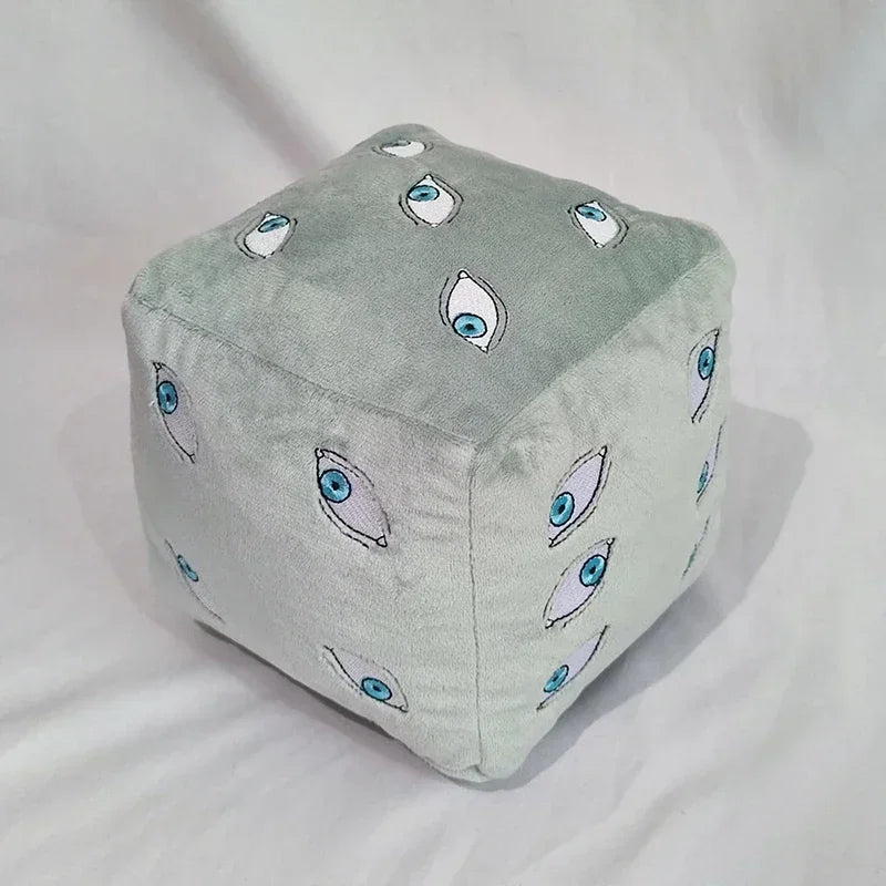 Coussin cube bleu clair en tissu doux, motifs d’yeux bleus sur toute la face.