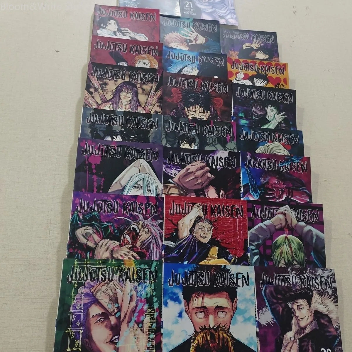 Stack of Jujutsu Kaisen manga volumes with colorful illustrated covers